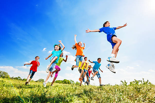 Happy children enjoying in the nature, they are jumping and having fun.