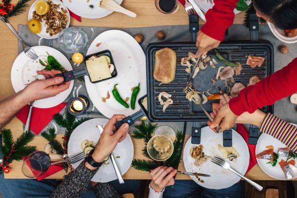 overhead view on family sitting around wooden table with raclette grill Labo trouille